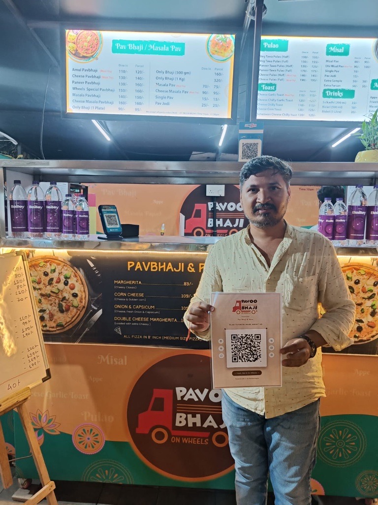 Pavoo Bhaji On Wheels owner holding a ReviewLoop QR flyer at the food counter